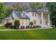 Elegant white brick home featuring a manicured lawn and lush landscaping at 5145 Saddlebred Ln, Cumming, GA 30028