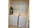 Laundry room features a white washer and dryer with shelving for storage at 2752 Inverloch Cir, Duluth, GA 30096