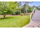 Grassy backyard features mature trees with stairs leading to the outdoor living space at 225 Carriage Station Cir, Roswell, GA 30075