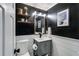 Stylish half bathroom with black walls, shiplap wainscoting, modern vanity, and decorative mirror at 225 Carriage Station Cir, Roswell, GA 30075