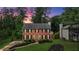 Charming two-story brick home boasts lush landscaping, a well-manicured lawn, and classic black shutters at dusk at 225 Carriage Station Cir, Roswell, GA 30075