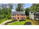Charming two-story brick home boasts lush landscaping, a well-manicured lawn, and classic black shutters at 225 Carriage Station Cir, Roswell, GA 30075