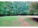 Expansive backyard featuring a well-kept lawn, surrounded by mature trees and a wooden fence at 5765 Woodstone Dr, Cumming, GA 30028