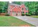 Charming two-story red brick home featuring a well-manicured lawn, attached two-car garage, and lush landscaping at 5765 Woodstone Dr, Cumming, GA 30028