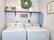 Functional laundry room featuring a washer, dryer, and decorative shelf with storage at 5765 Woodstone Dr, Cumming, GA 30028