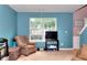 Cozy blue living room with a large window, comfortable armchair, and carpeted floors at 5765 Woodstone Dr, Cumming, GA 30028