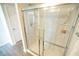 Bright bathroom featuring a glass-enclosed shower with tile surround and modern fixtures, with a white door and wooden flooring at 6011 Pine Bluff Pl, Conyers, GA 30013