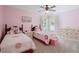 Bright pink bedroom featuring two beds, a ceiling fan, and a white dresser, creating a cozy and inviting space at 700 Mill Creek Cv, Canton, GA 30115