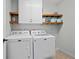 Clean laundry room with white washer and dryer, overhead cabinets and floating shelves at 700 Mill Creek Cv, Canton, GA 30115