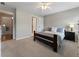 Comfortable bedroom features neutral carpet, a ceiling fan, and a dark wooden bed frame at 10135 High Falls Pointe, Johns Creek, GA 30022