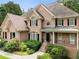 Charming two-story brick home featuring a well-manicured lawn and mature landscaping at 10135 High Falls Pointe, Johns Creek, GA 30022