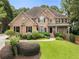 Charming two-story brick home featuring a well-manicured lawn and mature landscaping at 10135 High Falls Pointe, Johns Creek, GA 30022