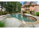 Beautiful pool and backyard view with a built-in jacuzzi, greenery, and stone trim at 10135 High Falls Pointe, Johns Creek, GA 30022