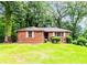Charming brick home featuring a lush green lawn and mature trees providing ample shade and curb appeal at 1913 Flintwood Se Dr, Atlanta, GA 30316