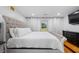 Bright bedroom features a tufted headboard, hardwood floors, and a window with sheer curtains at 2021 Sherwood Dr Se, Marietta, GA 30062
