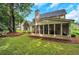 Backyard featuring well-manicured lawn, mature trees, and screened porch at 3522 Estates Landing Nw Dr, Kennesaw, GA 30144