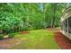Lush backyard with mature trees, green grass, and professionally landscaped areas near the house at 3522 Estates Landing Nw Dr, Kennesaw, GA 30144
