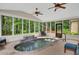 Heated indoor pool with stone waterfall and wooded views in a brightly lit sunroom at 3522 Estates Landing Nw Dr, Kennesaw, GA 30144
