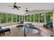 Bright sunroom features a heated pool with a stone waterfall, ceiling fans, and beautiful forest views at 3522 Estates Landing Nw Dr, Kennesaw, GA 30144