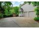 Side view of house with a 2-car garage, stone driveway, and backyard gate at 209 Breckenridge Ct, Canton, GA 30115