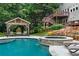 Beautiful backyard pool area featuring a hot tub with waterfall, a shaded pavilion, and comfortable lounge seating at 209 Breckenridge Ct, Canton, GA 30115