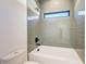 Bathroom with a bathtub and shower, featuring gray tile and a small window at 2551 Kilgore Rd, Buford, GA 30519