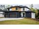 Modern two-story home with a black brick, white stucco, and natural wood exterior with a well-manicured lawn at 2551 Kilgore Rd, Buford, GA 30519