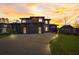 Modern home with a three-car garage and stylish accents, accentuated by a colorful sunset backdrop at 2551 Kilgore Rd, Buford, GA 30519