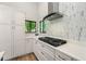 Contemporary kitchen has sleek white cabinetry, a modern range hood, and backyard views at 3430 Rocky Springs Ct, Marietta, GA 30062