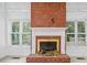 Close up of the brick fireplace with white mantle and hearth, flanked by two large windows at 5190 Beech Forest Sw Dr, Lilburn, GA 30047