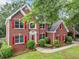 Two-story brick home with red shutters, green lawn, mature trees, and an inviting front entrance at 5190 Beech Forest Sw Dr, Lilburn, GA 30047