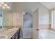 Bathroom with a tub, dark cabinets, a mirror, and a window at 2317 Church Street, Hampton, GA 30228