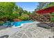 Inviting backyard pool area with stone tile deck, chaise lounges, shade umbrella, and mature trees at 64 Edwin Nw, Atlanta, GA 30318