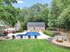 Expansive backyard with pool, lounge chairs, patio, fire pit, and lush landscaping at 704 Branchview Ct, Mcdonough, GA 30252