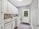 The laundry room has white cabinets, a utility sink, and a washer and dryer at 704 Branchview Ct, Mcdonough, GA 30252