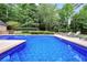 Backyard pool surrounded by lounge chairs, mature trees, and lawn at 704 Branchview Ct, Mcdonough, GA 30252