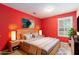 This staged bedroom features a queen bed with wood nightstands and an art piece on the red wall at 1908 Brittania Cir, Woodstock, GA 30188
