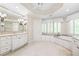 Bathroom with a soaking tub, custom cabinets, tile flooring, and a window with plantation shutters at 320 Yellowroot Ln, Sandy Springs, GA 30350