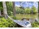 Scenic view of lake from a hammock, surrounded by lush greenery, offering a relaxing retreat at 3260 Kingshouse Commons, Johns Creek, GA 30022