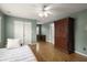 A bedroom features a ceiling fan, wood floors, and a large armoire for storage at 3260 Kingshouse Commons, Johns Creek, GA 30022
