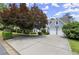 A well-maintained home featuring a three-car garage and a spacious driveway, complemented by lush greenery at 3260 Kingshouse Commons, Johns Creek, GA 30022