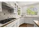 Kitchen featuring a gas cooktop, white cabinets, and a view from an arched window at 3260 Kingshouse Commons, Johns Creek, GA 30022