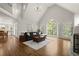 Bright living room with hardwood floors, vaulted ceiling, and large windows overlooking lush greenery at 3260 Kingshouse Commons, Johns Creek, GA 30022