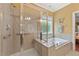 Bright bathroom boasts a glass shower, separate tub with decorative window, and neutral tile at 4535 Vanadium Bnd, Cumming, GA 30040