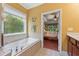 Bright bathroom features a soaking tub with decorative window and views into the main bedroom at 4535 Vanadium Bnd, Cumming, GA 30040