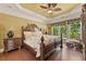 Serene main bedroom with a tray ceiling, a ceiling fan, and a view of the backyard at 4535 Vanadium Bnd, Cumming, GA 30040