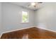 Bedroom features a ceiling fan, light paint, a window looking out to the front yard, and hardwood floors at 8185 Rivertown Rd, Fairburn, GA 30213