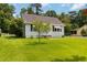 Traditional single-story home featuring a lush green lawn, mature trees, and quaint architectural details at 8185 Rivertown Rd, Fairburn, GA 30213