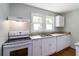Bright kitchen featuring a white oven, cabinets, marble countertops, and a stainless steel sink under a window at 8185 Rivertown Rd, Fairburn, GA 30213