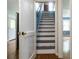 Stairway featuring hardwood floors, a white door, light paint, and a painted black and white staircase at 8185 Rivertown Rd, Fairburn, GA 30213